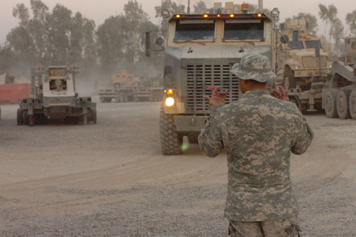 Soldier with Heavy Equipment Truck Transport (HETT) Platoon, 416th Transportation Company, 168th Brigade Support Battalion, 1st Sustainment Brigade, ground guides a HETT loaded with an MRAP out of their motor pool on 26 June 2008 in Iraq.  US Army Image
