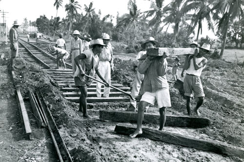 Filipino workers reconstructing the bombed and shelled tracks bridges and rail right of ways of the Manila Railroad to facilitate it use by the US Army.  Part of the research collection of the U.S. Army Transportation Museum.