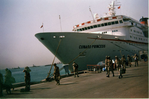Soldiers in desert camouflage walking past the 'Cunard Princess', a British luxury liner leased by the Department of Defense to provide an R & R location to troops during Desert Storm/Desert Shield.  Part of the research collection of the U.S. Army Transportation Museum.
