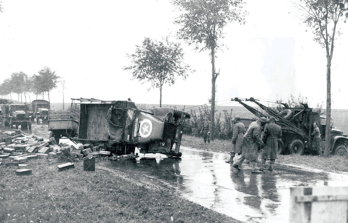 A road patrol wrecker (right) pulls an overturned truck back on its wheels circa 1944 to haul it to the nearest heavy-automotive maintenance depot along the Red Ball Express route in the European theater of operations. Damaged trucks were repaired at once and put back into service. If a truck was damaged beyond repair, it was immediately replaced. (Photo by Lawrence Riordan/U.S. Army)