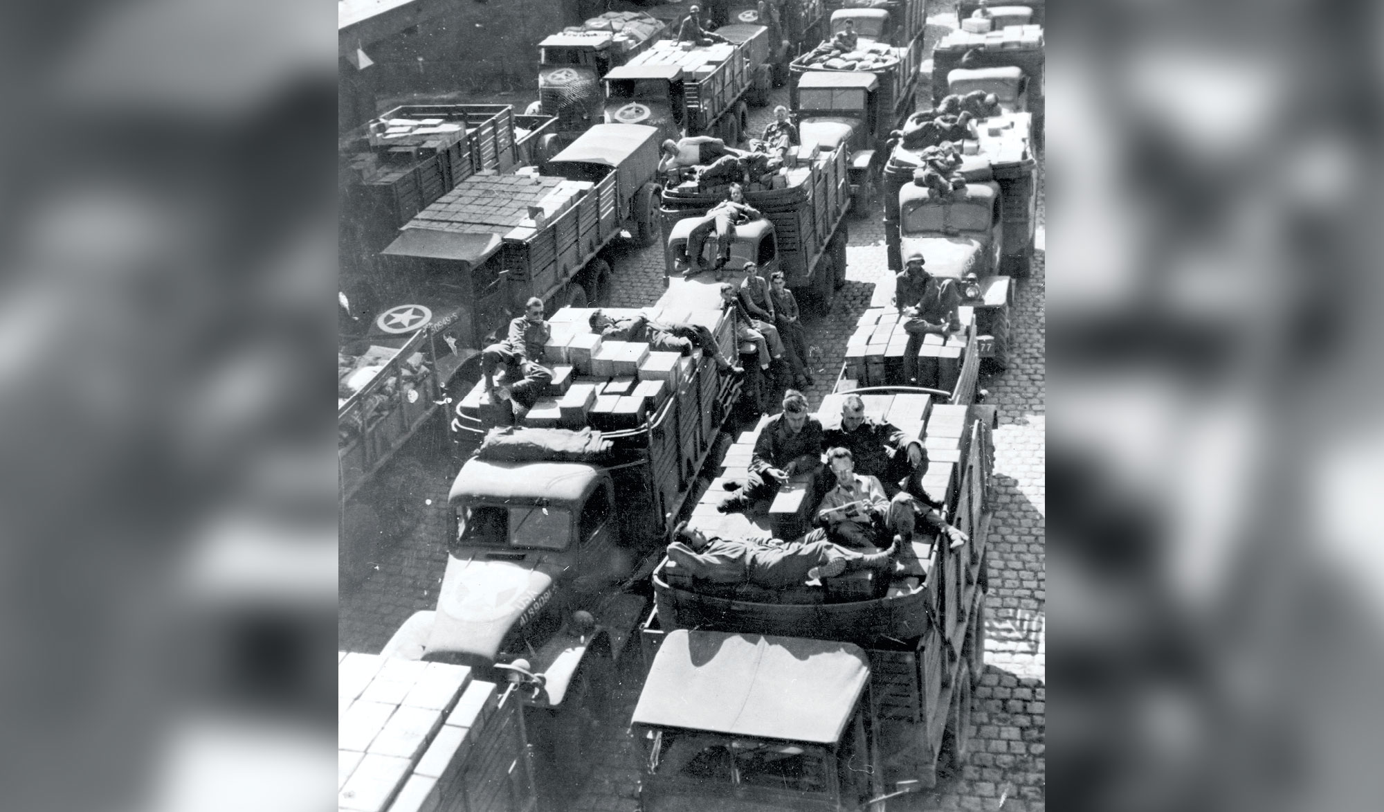 U.S. drivers nap or relax on boxes of ammunition and other equipment 10 October 1944 during the delivery of supplies to a forward area in France. The supply train is one of the Red Ball convoys that constituted an endless chain of trucks operating to and from the front on one-way roads. The highways were marked with Red Ball priority signs and were reserved for urgent supplies. (Photo courtesy of the U.S. Army)