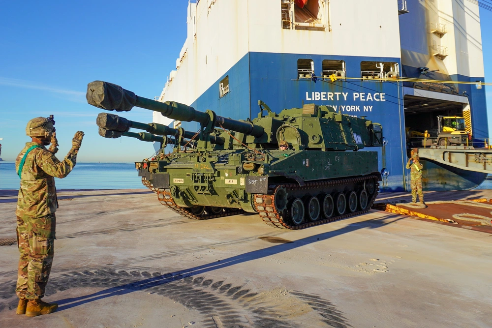 Photo By Capt. Misael Saldivar | M109 Paladin driver Pfc. Sterling Maness and ground-guide Staff Sgt. Stephon McIntosh communicate through hand signals to stage the howitzer at its proper location within the staging yard during offloading operations at the port of Koper, Slovenia on December 28, 2024.