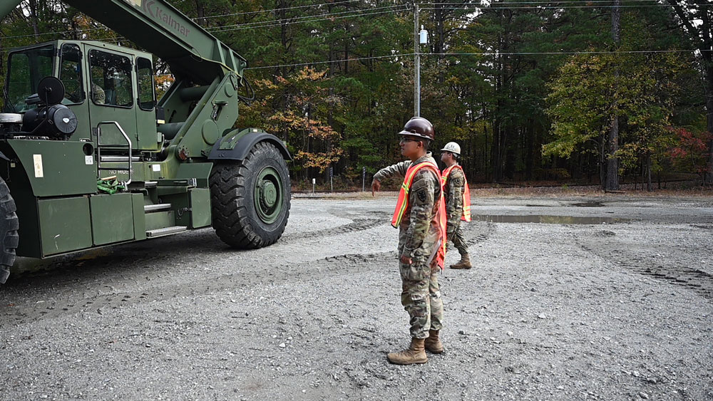 U.S. Army Pfc. Justin Blakeslee, left, and U.S. Army Sgt. Isaac Rosas, with the 331st Transportation Company, provide additional guidance to a Rough Terrain Cargo Handler loading a container onto a rail car at Joint Base Langley-Eustis, Virginia, November 16, 2022, as a part of Operation Deep Freeze. The supplies within the containers will support the 3,200 scientists, researchers, and support personnel at McMurdo Station, Antarctica. (U.S. Air Force photo by Abraham Essenmacher