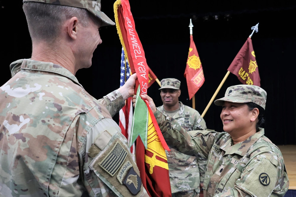 Lt. Col. Michelle P. Santayana passes the unit colors to Col. Eric W. Anderson, commander of the 595th Transportation Surface Brigade (SDDC), during a change of command ceremony at Naval Support Activity Bahrain, May 30, 2024.