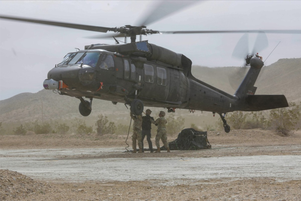 Soldiers sling load cargo for a UH-60A Blackhawk during an autonomous flight as part of persistent experimentation at Project Convergence - Capstone 4, Fort Irwin, Calif., on March 10, 2024. During Project Convergence in 2022 at Yuma Proving Ground, Ariz., a Blackhawk, using an autonomous system, performed three missions without a pilot. (U.S. Army photo by Spc. Zion Thomas)