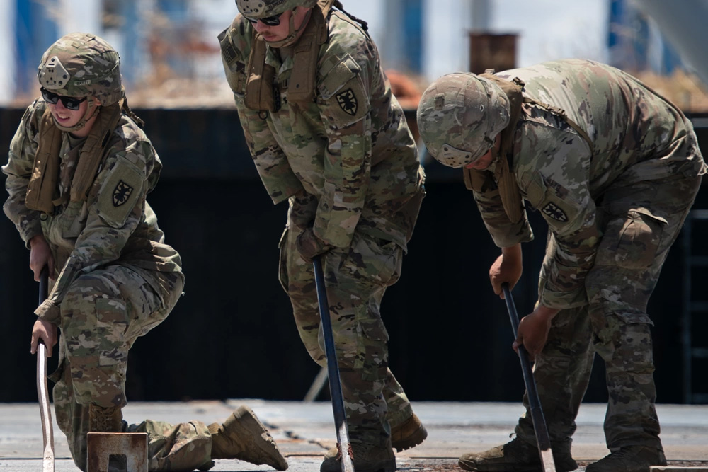 U.S. Army Spc. Briar Chasteen, middle, uses a metal rod to assemble a section of the Trident Pier, in the Port of Ashdod, Israel, May 6, 2024.