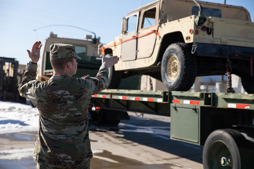 U.S. Army Reserve Sgt. Jace Schwager, an Army Motor Transport Operator with the 425th Transportation Company, directs the unloading of a humvee at the JP Martinez Army Reserve Center, Denver, Colorado, Feb. 5, 2023. Trucks were loaded onto ramps where HUMVEEs and other equipment were unloaded. (U.S. Army photo by Spc. Addison Shinn)
