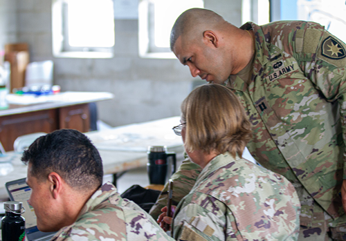Army Capt. Rafael Vega (right), operations officer, and Army Staff Sgt. Angela Engle (center), CBRN noncommissioned officer, discuss training updates displayed on Engle’s computer screen while participating in a staff exercise during annual training at Camp Blanding, Florida, on June 12, 2023. Engle and Vega are assigned to the 254th Transportation Battalion, a Florida Army National Guard unit headquartered in West Palm Beach, Florida. (U.S. Army Guard photo by Sgt 1st Class Shane Klestinski)